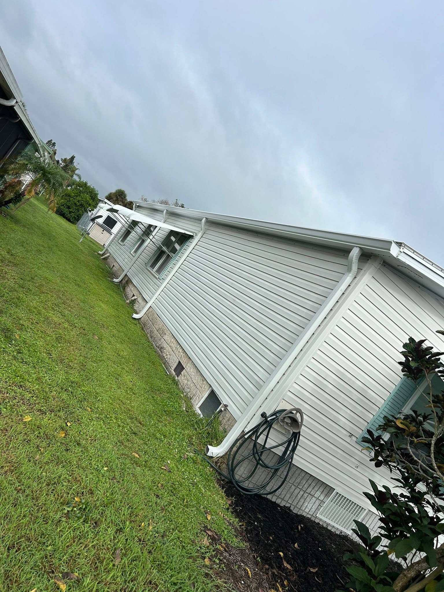 White-sided Brevard County home with seamless gutters and downspout